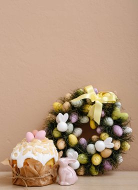 Pasta ve tavşanlı Paskalya çelengi bej duvarın yanındaki masada.