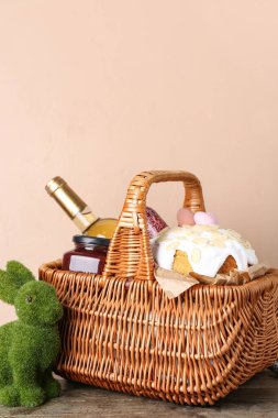 Paskalya yumurtası, pasta ve şarap dolu sepet bej arka planda.
