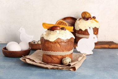 Hayvan figürlü Paskalya pastaları ve beyaz duvarın yanındaki mavi grunge masasında yumurtalar.