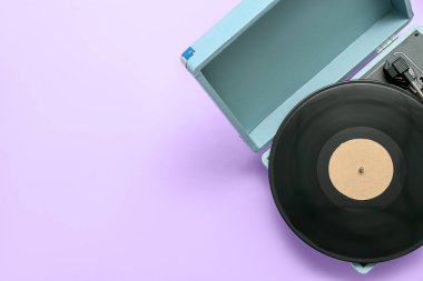 Leylak arka planında vinil diski olan bir kayıt oynatıcı