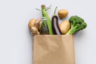 Gri arka planda taze sebzeli kağıt alışveriş torbası.