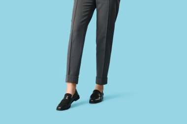 Mavi arka planda şık siyah ayakkabılı genç kadın bacakları.