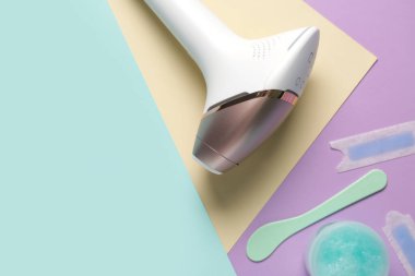 Balmumu şeritli modern fotoepilatör ve renk arkaplanındaki fırça kavanozu