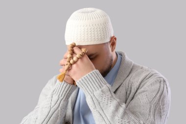Hafif arkaplanda tespih taşıyan genç Müslüman adam, yakın plan. Ramazan kutlaması