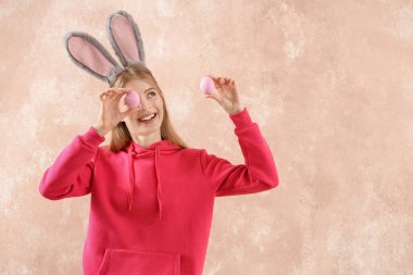 Paskalya yumurtası ve paskalya arkaplanda tavşan kulaklı genç kadın.
