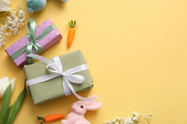 Paskalya tavşanı hediye kutuları ve turuncu arka planda çiçekler.