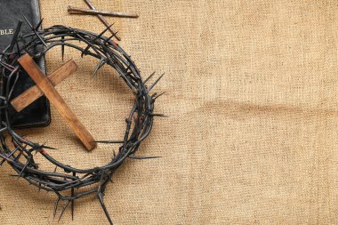 Ahşap haçlı dikenli taç, kumaş arka planda İncil ve çiviler