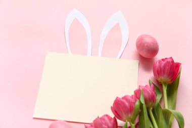 Yaratıcı kompozisyon, boş kart, laleler ve pembe arka planda yumurta. Paskalya kutlaması