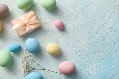 Boyanmış Paskalya yumurtaları, çingene çiçekleri ve mavi grunge arka planda hediye kutusu.