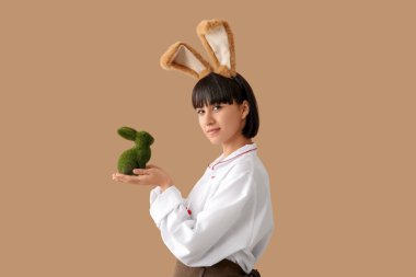 Kahverengi arka planda Paskalya tavşanı olan tavşan kulaklı kadın şef.