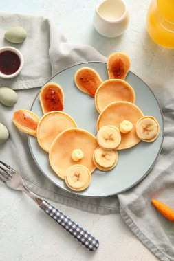 Açık mavi arka planda boyalı yumurtaları olan komik Paskalya tavşanı krepleri.