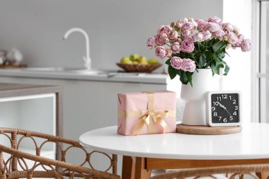 Güllü vazo, Uluslararası Kadınlar Günü için hediye kutusu ve mutfaktaki masada saat.