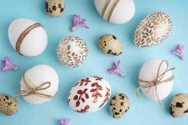 Mavi arka planda süslü Paskalya yumurtaları ve mor çiçekler.