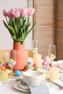 Laleler, mumlar, boyanmış yumurtalar ve Paskalya 'dan oluşan bir ziyafet masası.