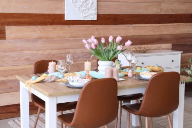 Paskalya sofrası ve sandalyeleri olan dekoratif yemek odasının içi.