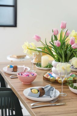 Paskalya sofrası, boyalı yumurta, çatal bıçak takımı ve çiçek vazosu.