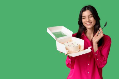 Yeşil arka planda tatlı bento keki ve çatalı olan güzel bir kadın. Uluslararası Kadınlar Günü