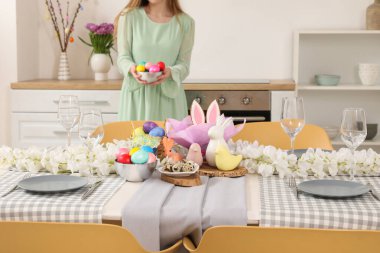 Paskalya sofrasını boyalı yumurtalarla süsleyen kadın.