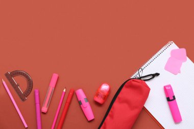 Not defteri, kalem kutusu ve kırmızı arka planda kırtasiye malzemesi. Üst görünüm