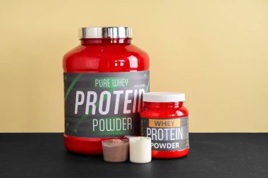 Koyu renkli masa üzerinde protein tozu bulunan şişeler ve kepçeler renk arka planına karşı