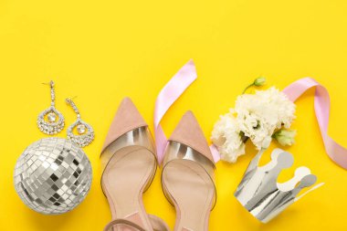 Şık topuklu kağıt taç, disko topu, küpeler ve sarı arka planda güzel çiçekler. Balo konsepti