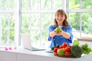 Ofiste oturan elmalı kadın beslenme uzmanı.