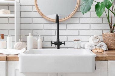 Banyo malzemeleri, raf ve lavabo banyodaki beyaz tuğla duvarın yanında.