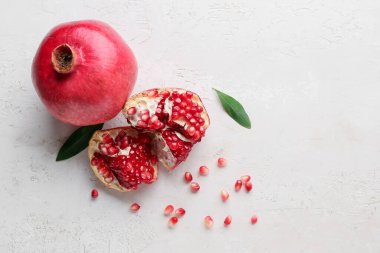 Beyaz zemin üzerinde tohum ve yapraklarla taze olgun nar.