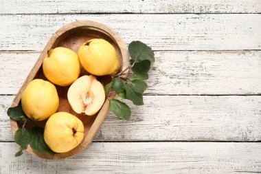 Tatlı olgun ayva tepsileri ve beyaz ahşap arka planda yapraklar