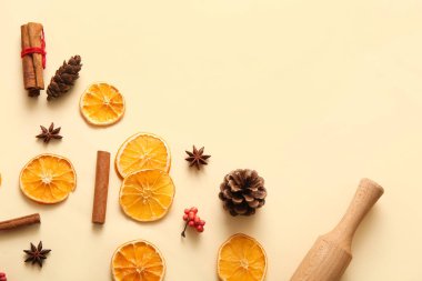 Dried orange slices with cinnamon, star anise and pine cones on yellow background