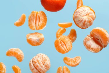 Mavi arka planda soyulmuş tatlı mandalinalar uçuyor