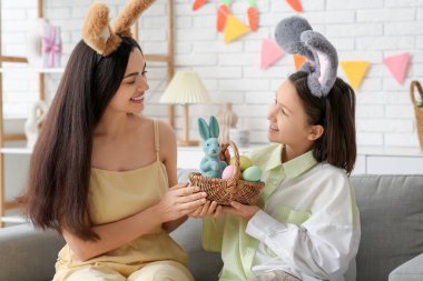 Küçük kız ve annesi ellerinde paskalya yumurtalarıyla dekore edilmiş oturma odasında.