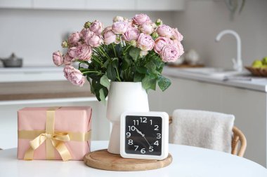 Güllü vazo, Uluslararası Kadınlar Günü için hediye kutusu ve mutfaktaki masada saat.