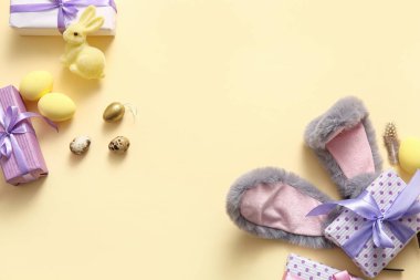 Paskalya yumurtalı tavşan kulakları ve bej arka planda hediye kutuları.