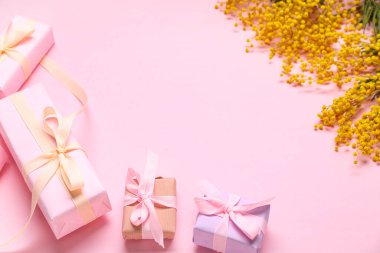 Hediye kutularıyla kompozisyon ve pembe arka planda mimoza.