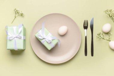 Yeşil arka planda hediyeler, çiçekler ve yumurtalarla güzel bir Paskalya masası.