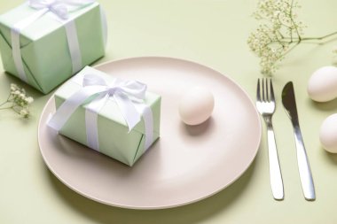 Yeşil arka planda hediyeler, çiçekler ve yumurtalarla güzel bir Paskalya masası.