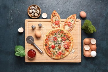 Tavşan kulaklı lezzetli Paskalya pizzası, siyah arka planda yumurta ve sos.