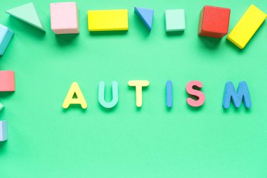 Yeşil arkaplanda renkli blokları olan sözcük AUTISM