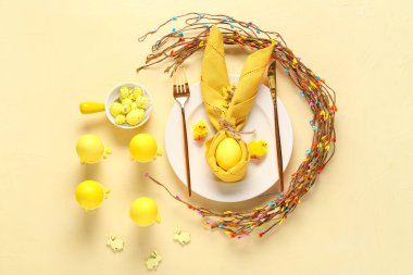 Sarı arka planda boyanmış yumurtalarla Paskalya kutlaması için şık bir masa. Üst görünüm