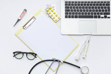 Blank clipboard with medical supplies and laptop on white background. World Health Day