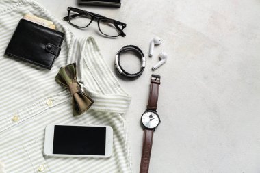 Açık arkaplanda şık erkek aksesuarları, gömlek ve cep telefonu kompozisyonu