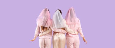 Pijamalı ve peçeli genç kadınlar leylak arka planda sarılıyorlar. Kız Partisi