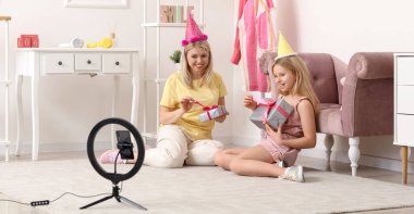 Mutlu kadın blogcu ve kızı evde hediye videosu kaydediyor.