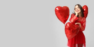 Gri arka planda kalp şeklinde balonları olan mutlu genç bir kadın ve mesaj için yeri var. Sevgililer Günü kutlaması