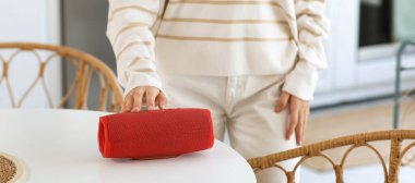 Mutfaktaki masadaki kablosuz hoparlörlü kadın.