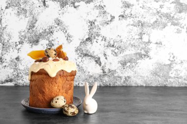 Paskalya pastası tavşan figürlü ve bıldırcın yumurtaları açık grunge duvarının yanındaki karanlık masada.