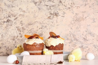 Tavuklu Paskalya pastası ve bej rengi grunge duvarın yanındaki beyaz ahşap masada yumurtalar.