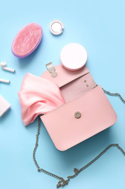 Kulaklıklı şık bir çanta ve mavi arka planda farklı aksesuarlar.