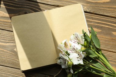 Boş bir defter ve ahşap arka planda güzel alstromerya çiçekleri.